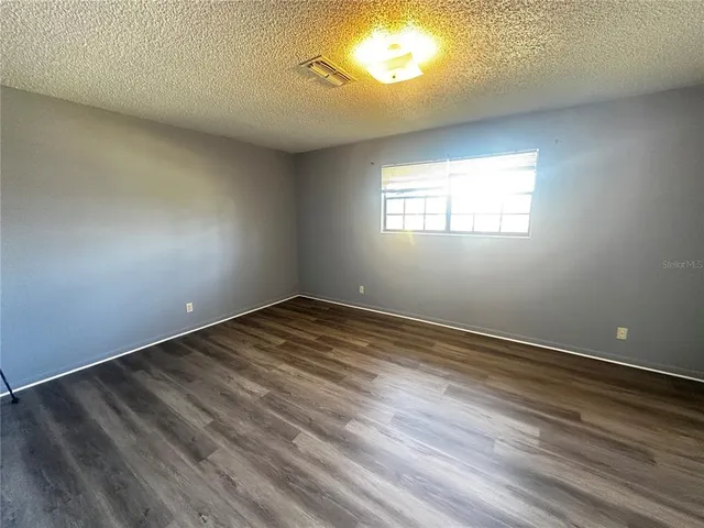 en empty room with wooden floor and windows