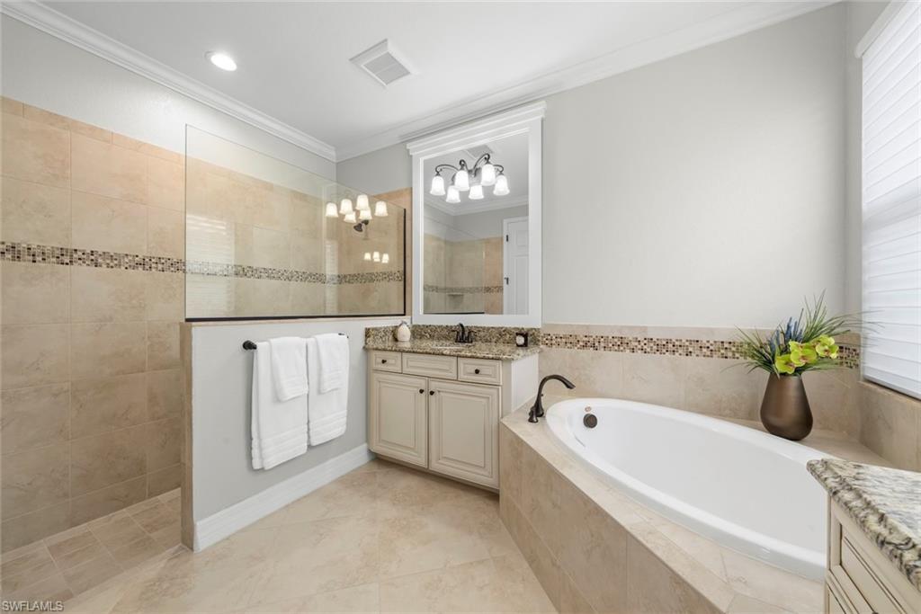 12692 Kinross Lane Naples, FL 34120 - Photo 20 of 47 Primary bathroom with tiled walk-in shower with a glass enclosure, separate soaking tub, and a dual vanity with granite countertops