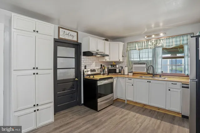 a kitchen with granite countertop a refrigerator a sink and white cabinets