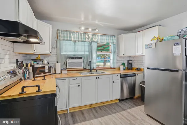 a kitchen with a sink a refrigerator and a stove top oven