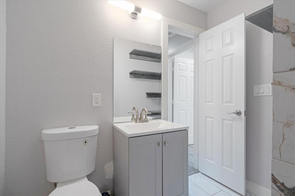 112 North Masters Drive Dallas, TX 75217 - Photo 16 of 22 a bathroom with a sink a toilet a mirror and shower