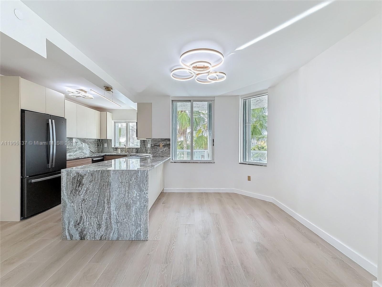 5900 Collins Avenue, Unit 508 Miami Beach, FL 33140 - Photo 9 of 39 a kitchen with a wooden floor cabinets and stainless steel appliances