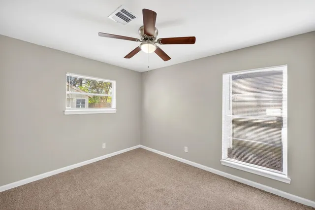 en empty room with windows and ceiling fan