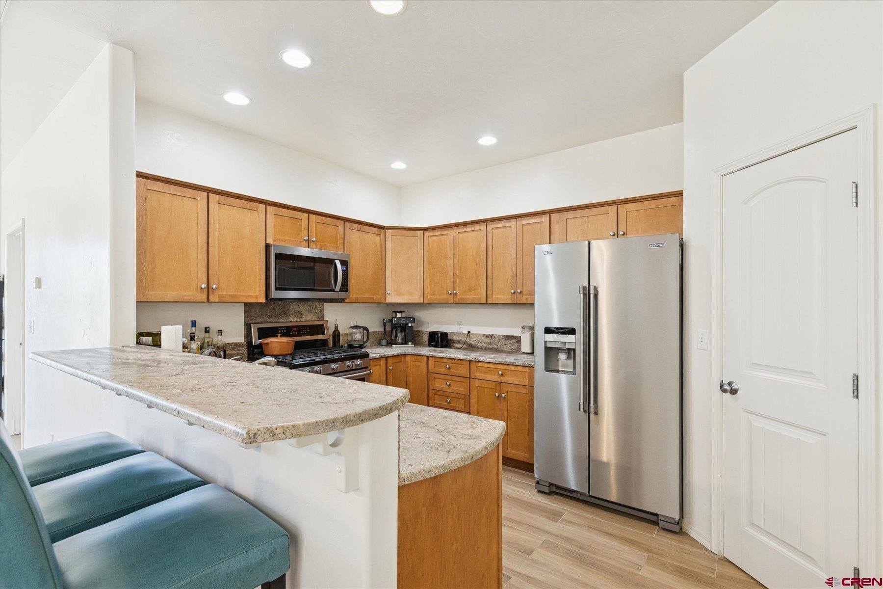 721 Arbor Street Cortez, CO 81321 - Photo 3 of 16 a kitchen with a refrigerator a stove top oven a sink and dishwasher with wooden floor