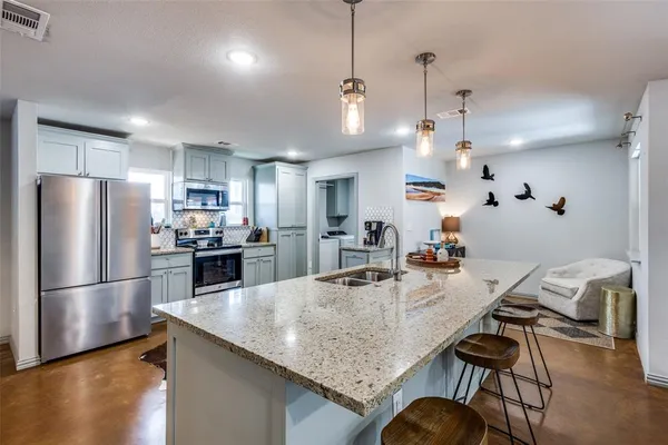 a kitchen with granite countertop a table chairs stainless steel appliances and wooden floor