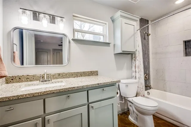 a bathroom with a granite countertop toilet sink and mirror