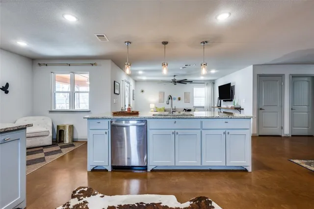 a kitchen with kitchen island granite countertop a sink cabinets and wooden floor