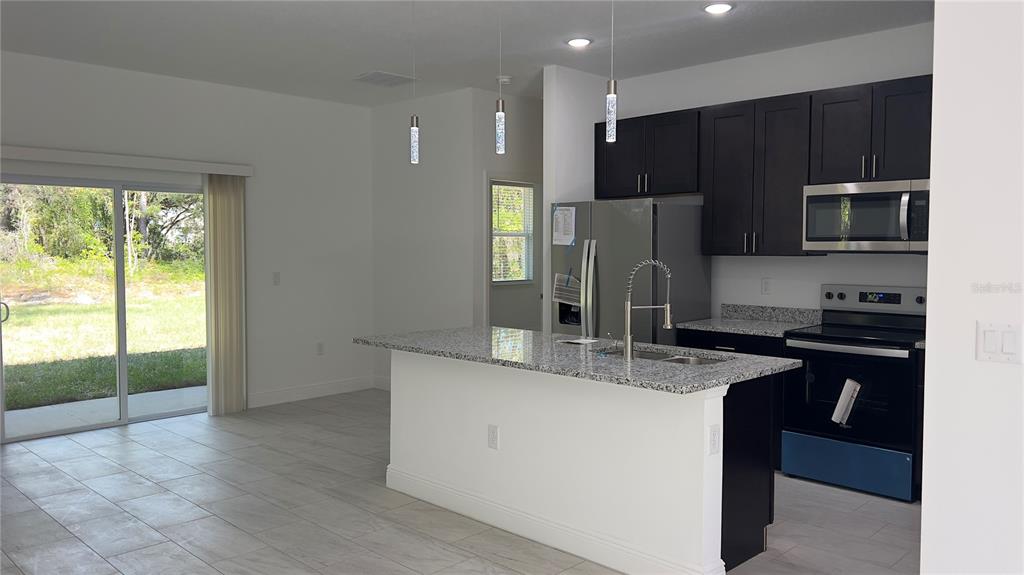 5027 Southwest 165th St Road Ocala, FL 34473 - Photo 12 of 33 a kitchen with kitchen island granite countertop a stove refrigerator and microwave