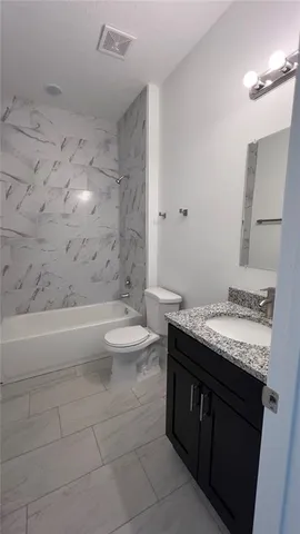 a bathroom with a granite countertop sink a toilet and bathtub
