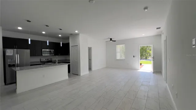 a view of kitchen with kitchen island granite countertop stainless steel appliances stove refrigerator and microwave