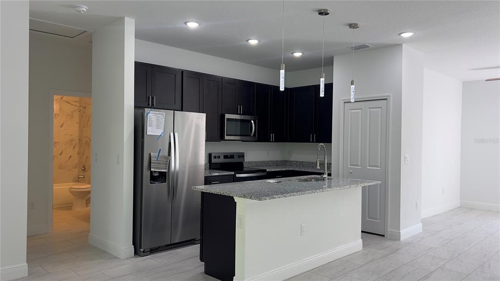 5027 Southwest 165th St Road Ocala, FL 34473 - Photo 7 of 33 a kitchen with stainless steel appliances granite countertop a refrigerator a sink and a stove