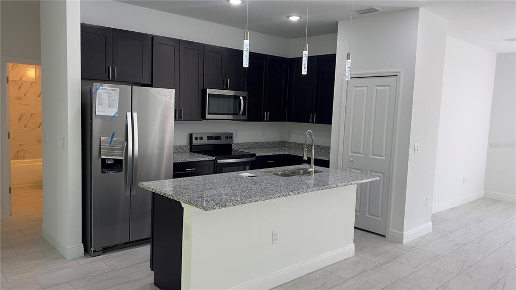 5027 Southwest 165th St Road Ocala, FL 34473 - Photo 10 of 33 a kitchen with stainless steel appliances granite countertop a refrigerator a sink a stove a microwave and island