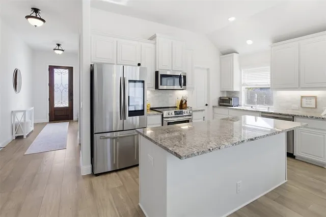 a kitchen with a dining table chairs refrigerator and cabinets