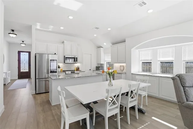 a kitchen with a dining table chairs and refrigerator