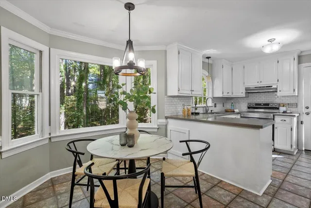 a kitchen with stainless steel appliances a dining table chairs and white cabinets