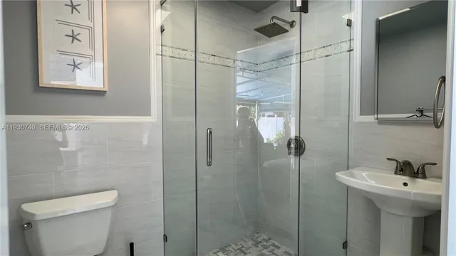 a bathroom with a shower a sink and toilet