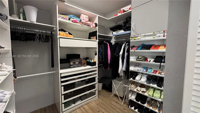 a view of walk in closet with clothes and shoes