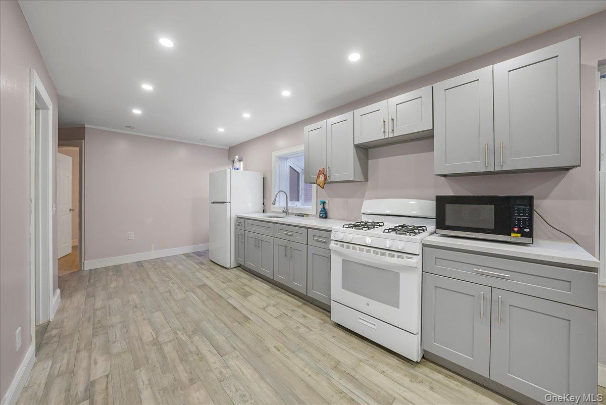 1526 Kennellworth Place Bronx, NY 10465 - Photo 27 of 37 a kitchen with white cabinets stainless steel appliances and sink