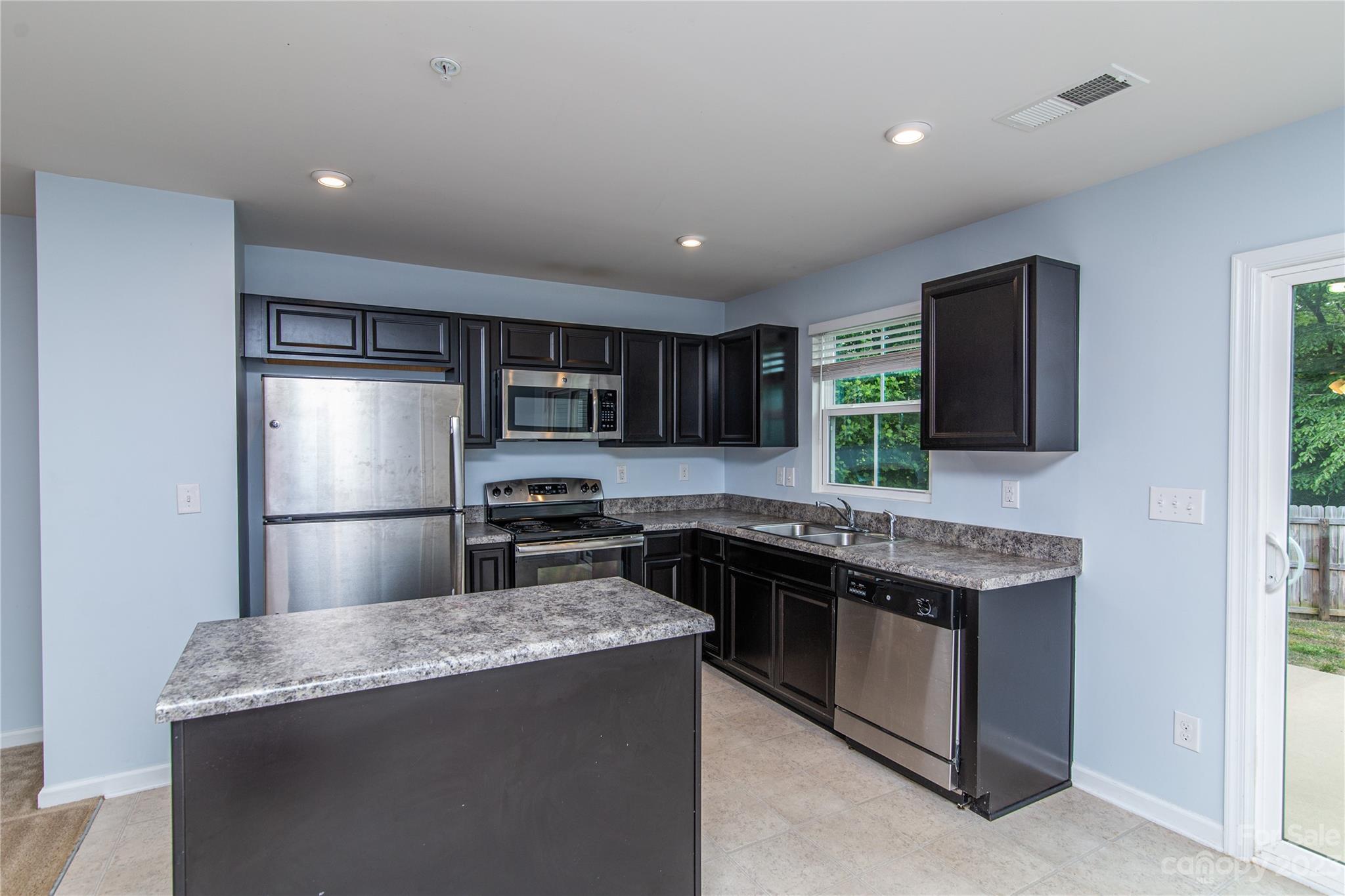 1151 Tangle Ridge Drive Southeast Concord, NC 28025 - Photo 7 of 22 a kitchen with stainless steel appliances granite countertop a sink stove and refrigerator
