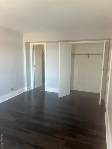 a view of an empty room with wooden floor and closet