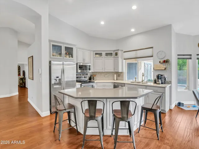 a kitchen with stainless steel appliances kitchen island granite countertop a dining table chairs and refrigerator