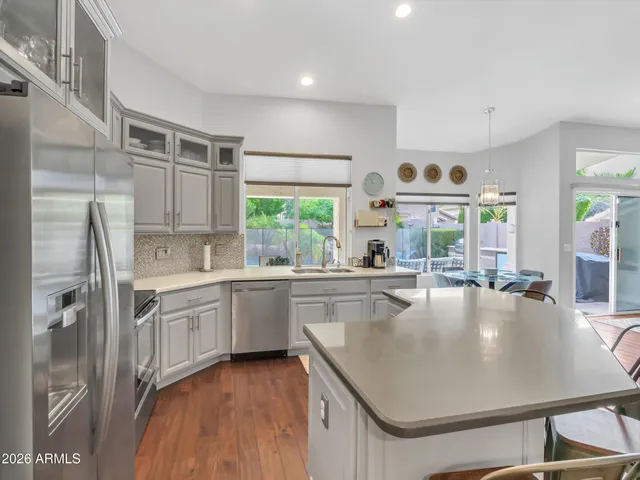 a large kitchen with kitchen island a large window a sink and stainless steel appliances