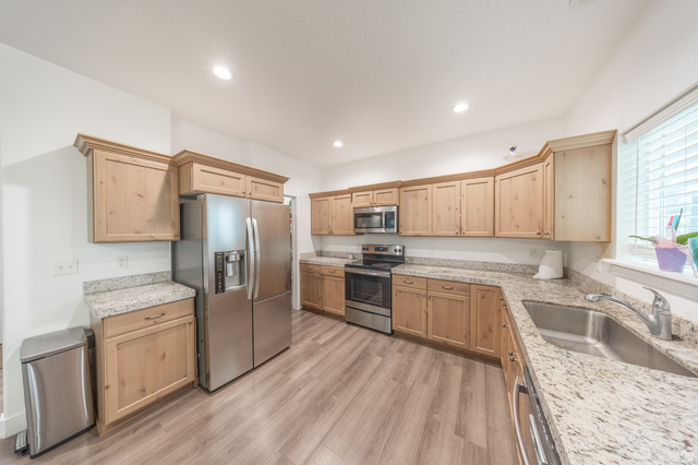 4765 Breezy Patch Road Eagle Mountain, UT 84005 - Photo 9 of 25 Kitchen featuring wood-finish cabinetry, light-toned countertops, and wood-finish flooring