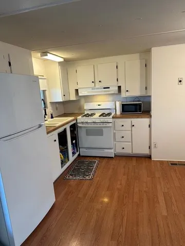 a kitchen with granite countertop a stove a sink and a refrigerator