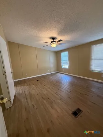 a view of an empty room with window and wooden floor