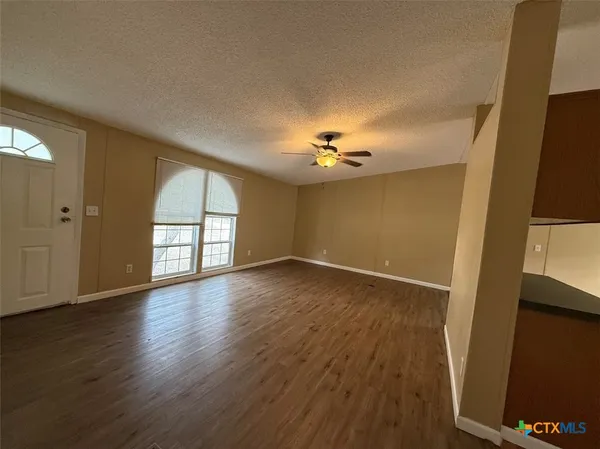 a view of an empty room with wooden floor and a window