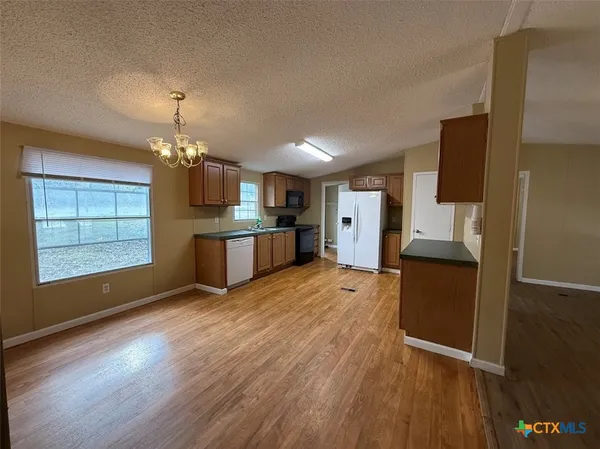 a open kitchen with a refrigerator and a stove top oven