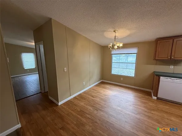 an empty room with wooden floor cabinet and windows
