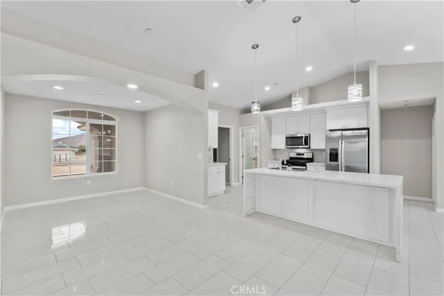 a large white kitchen with kitchen island a stove a sink a refrigerator and a cabinets