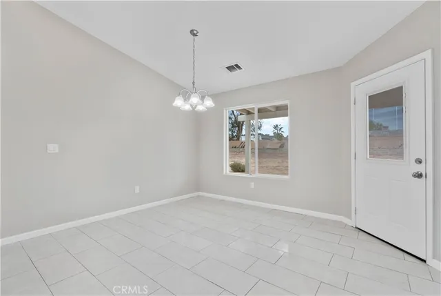 an empty room with chandelier fan and windows