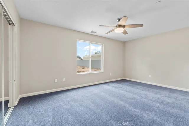 an empty room with windows and fan