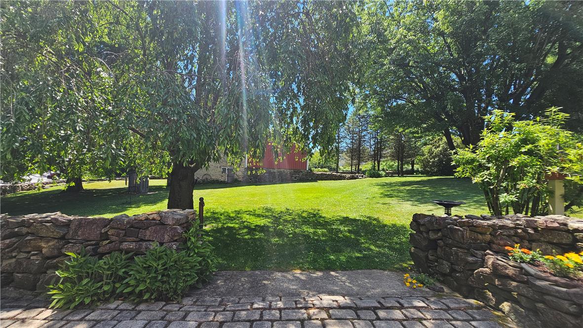 585 Buttermilk Road Hellertown, PA 18055 - Photo 58 of 82 A verdant outdoor sanctuary awaits, framed by mature trees and a rustic stone wall.