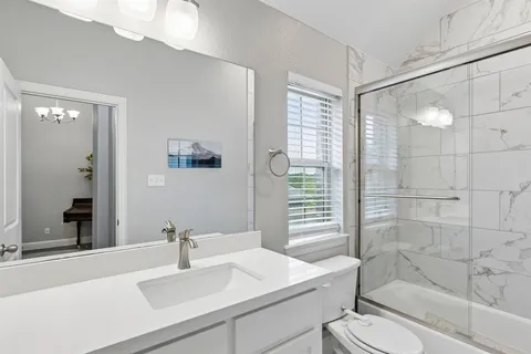 a bathroom with a sink a toilet a mirror and shower