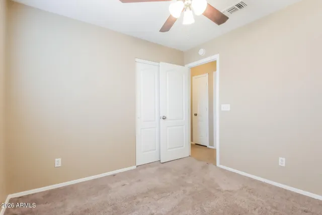 an empty room with closet and a chandelier fan