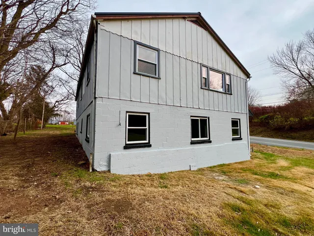 a view of house with backyard and trees in the background