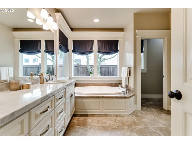 a spacious bathroom with a tub sink and mirror