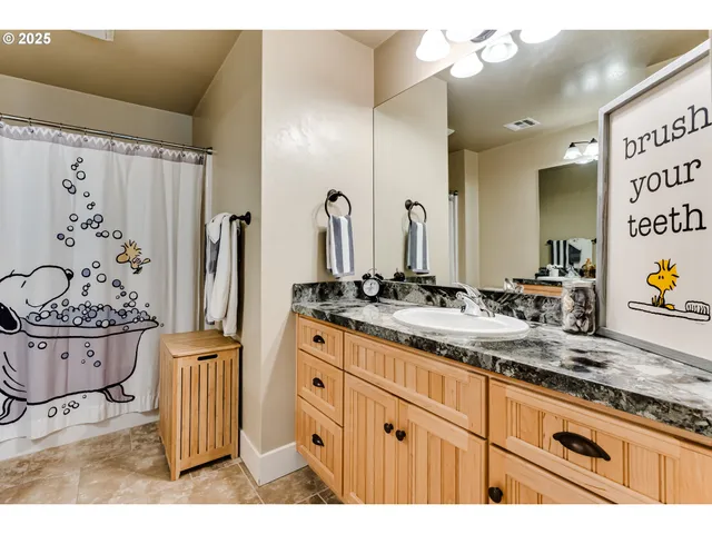a bathroom with a granite countertop sink a mirror and a shower