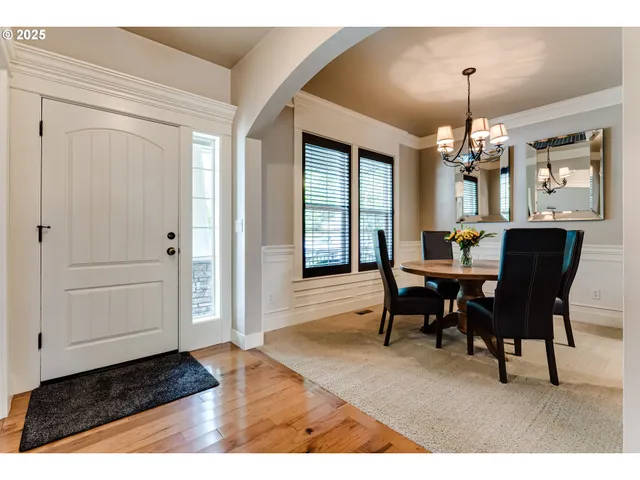 a dining room with wooden floor a chandelier a wooden table and chairs