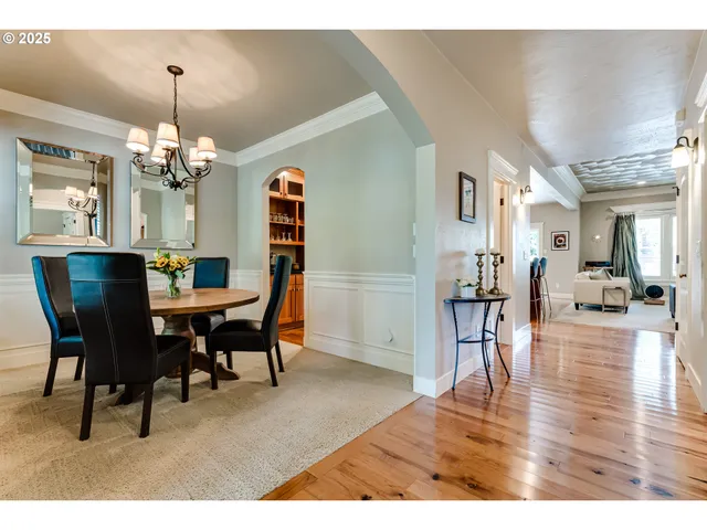 a dining room with wooden floor a chandelier a wooden table and chairs