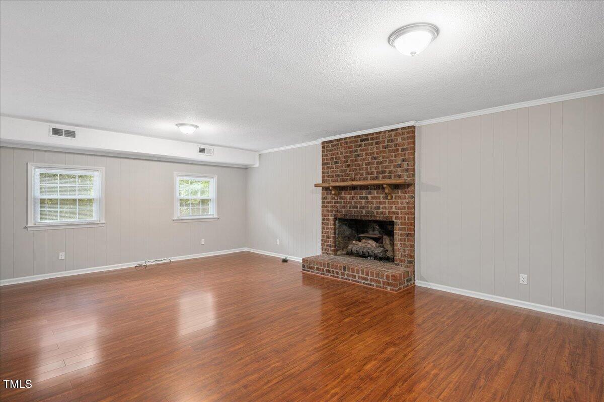 5812 Old Forge Circle Raleigh, NC 27609 - Photo 15 of 31 an empty room with wooden floor fireplace and windows