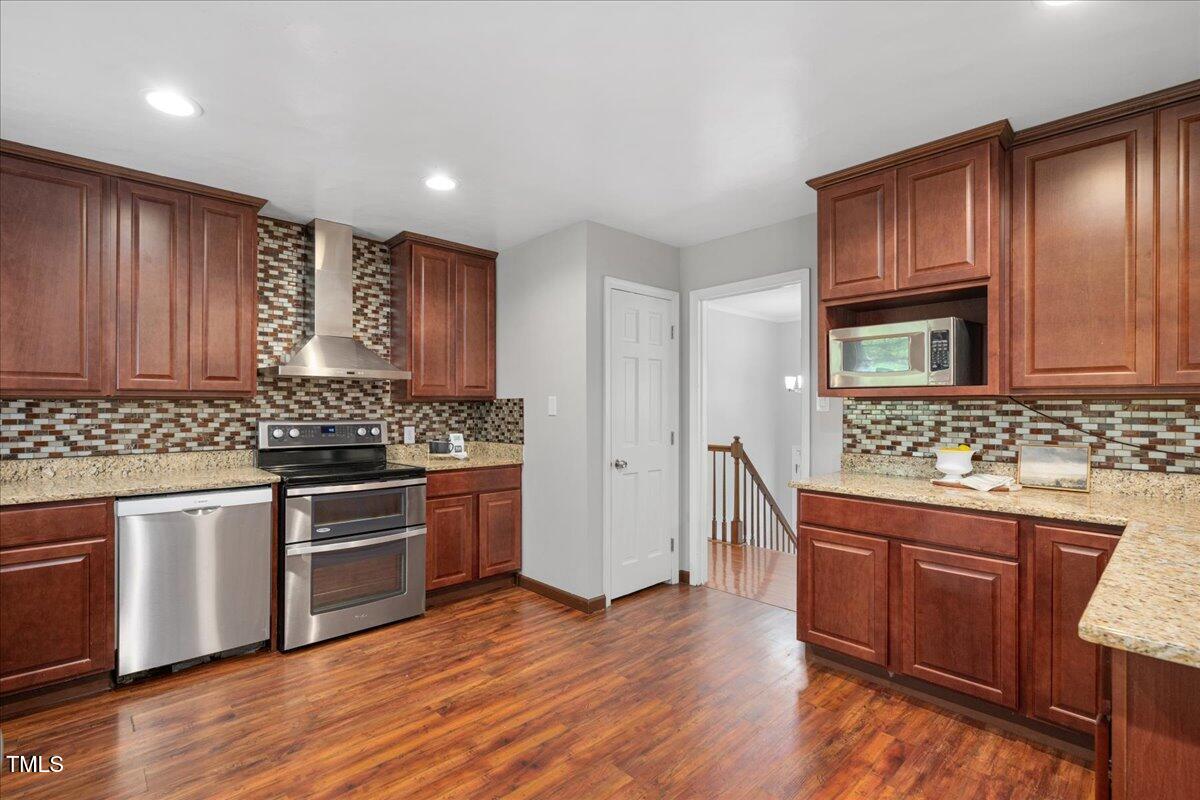 5812 Old Forge Circle Raleigh, NC 27609 - Photo 3 of 31 a kitchen with stainless steel appliances granite countertop wooden cabinets a stove a sink and dishwasher with wooden floor
