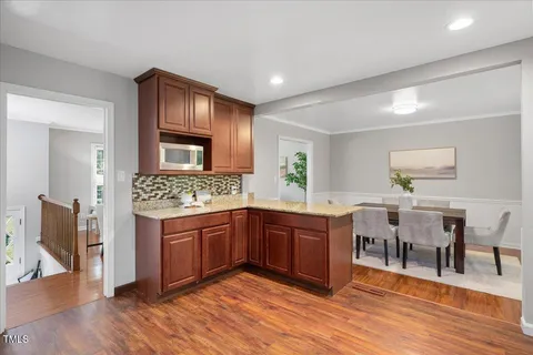 a large kitchen with kitchen island granite countertop wooden floors and white cabinets