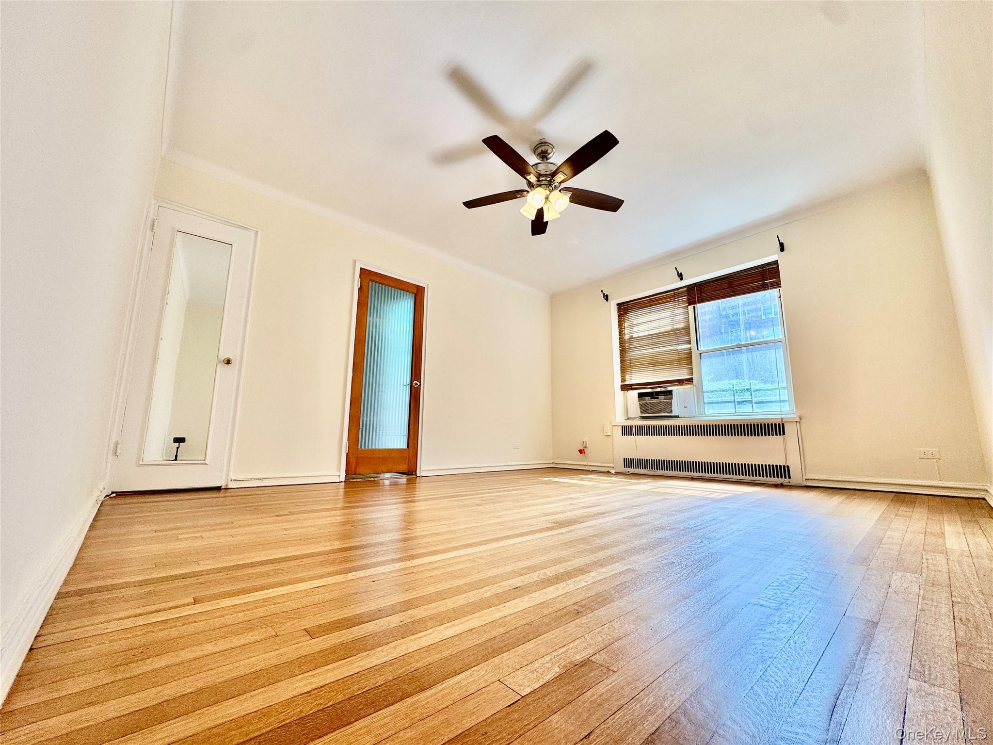 113-14 72nd Road, Unit 1M Queens, NY 11375 - Photo 16 of 20 a view of an empty room with wooden floor and a ceiling fan