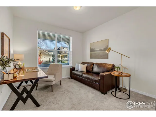 a living room with furniture a rug potted plant and a window