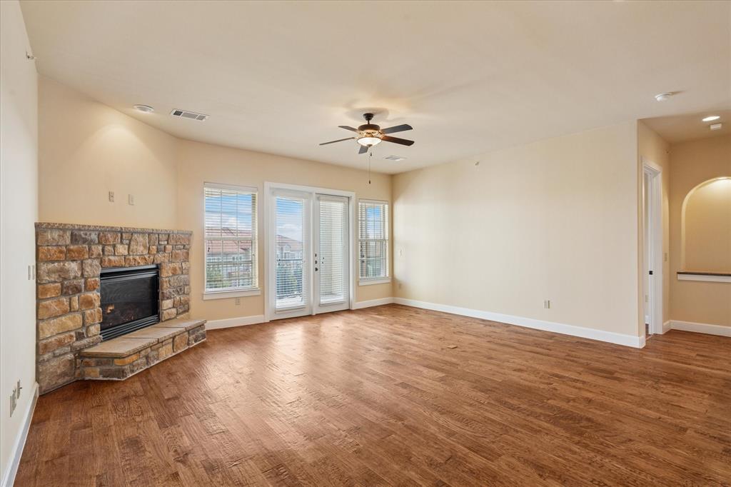 610 Via Ravello, Unit 410 Irving, TX 75039 - Photo 7 of 28 an empty room with windows fireplace and a kitchen view