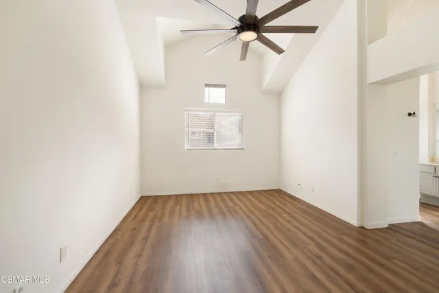 an empty room with wooden floor fan and windows